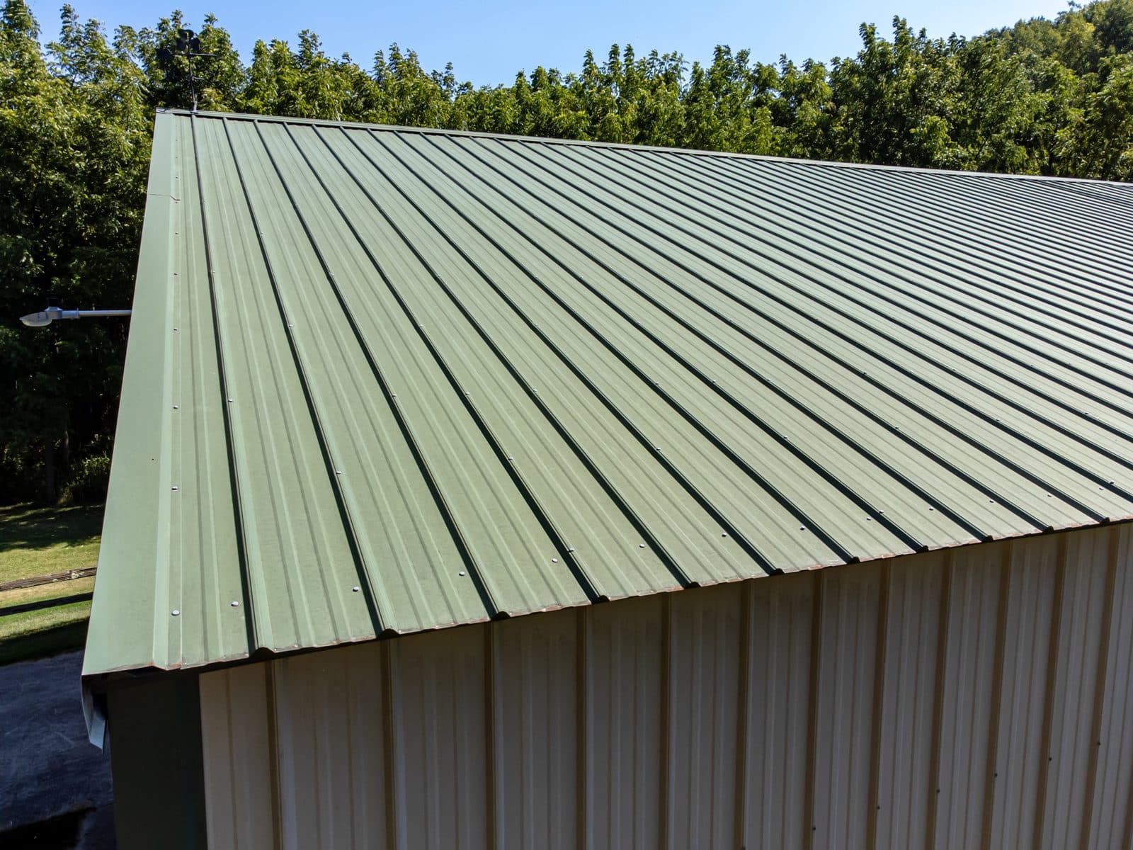 Close-up of a ribbed corrugated metal roof with rows of exposed screws installed through the face of the panels