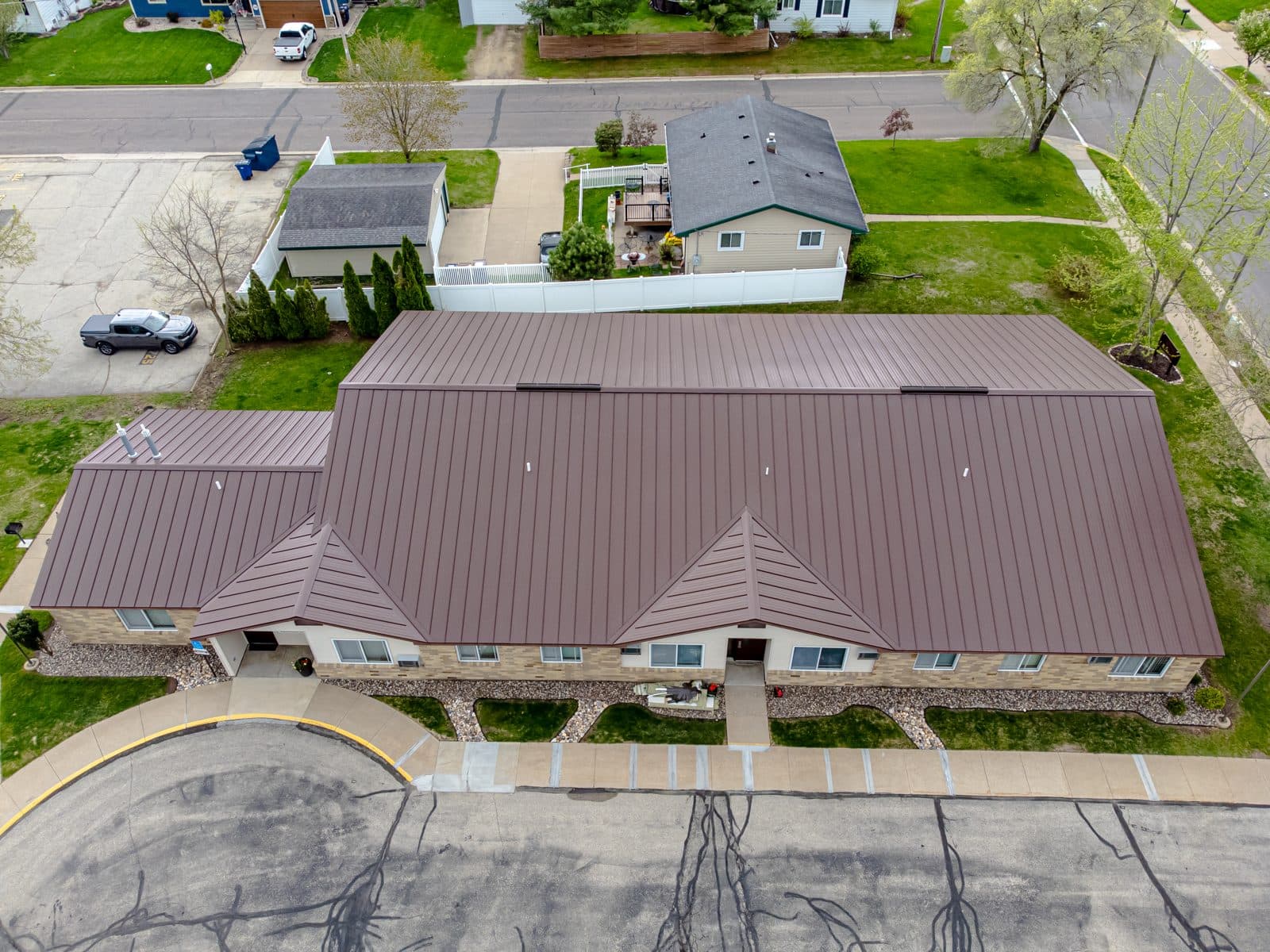 Aerial view of a long single-story building with a brown standing seam metal roof