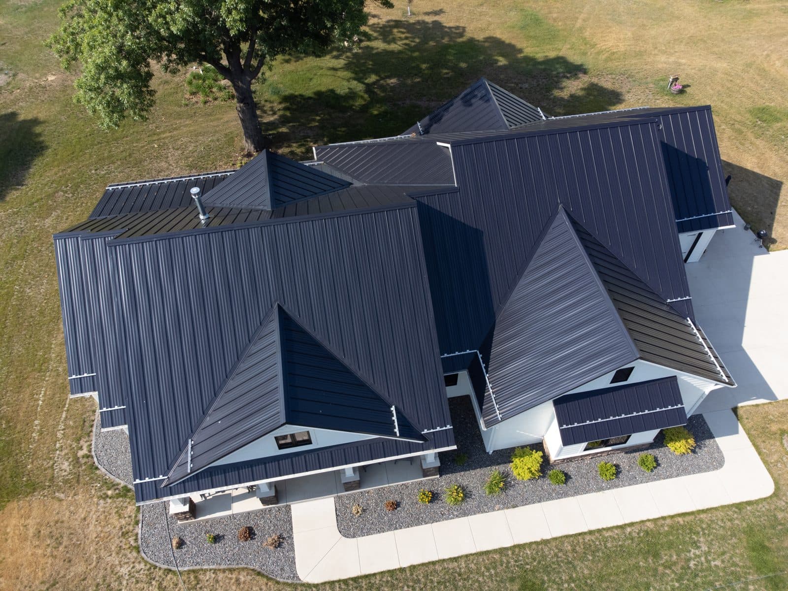 Aerial view of a home with a dark standing seam metal roof showing clean vertical seams and no exposed fasteners