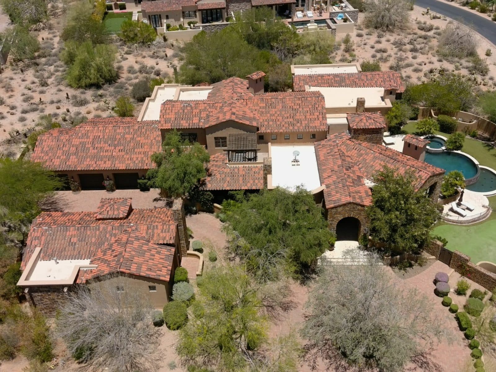 Aerial view of a large Arizona home with a clay tile roof surrounded by desert landscaping