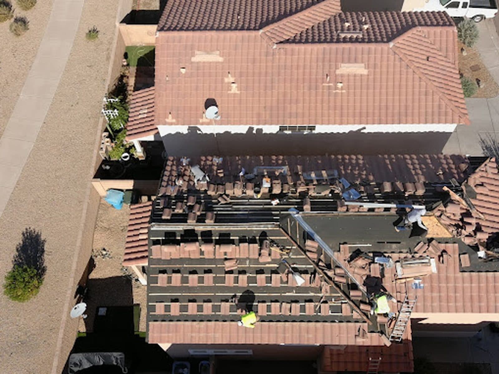 Aerial view of a tile roof relay job on an Arizona home, with sections of tile removed and stacked while crews work on the exposed roof deck
